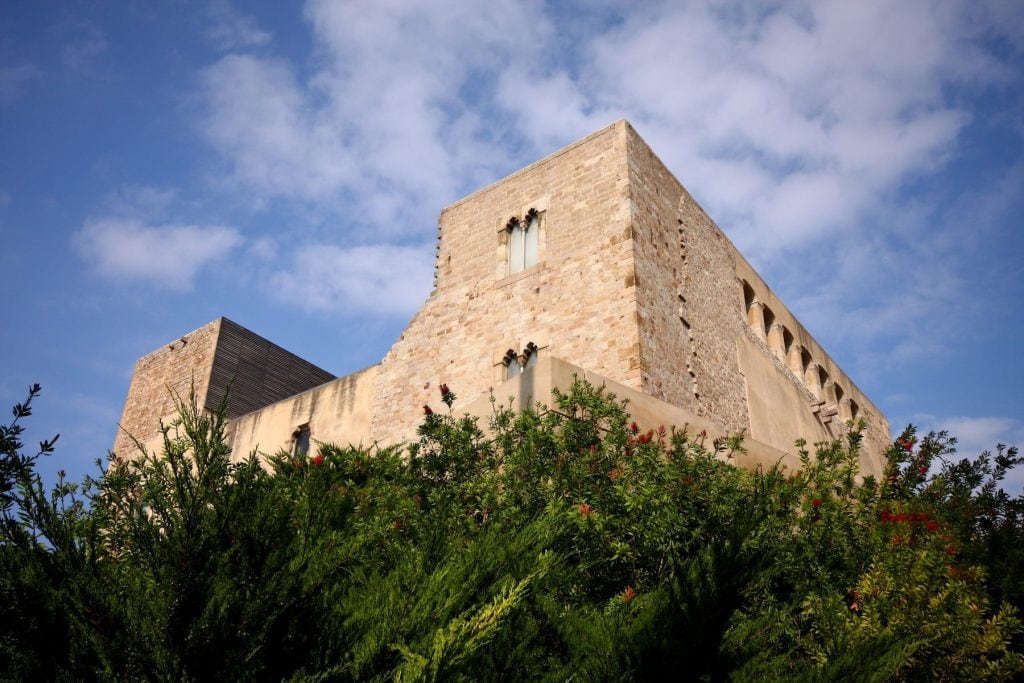 Torre y muros de piedra del Castell de Cornellà entre vegetación, en Cornellà de Llobregat