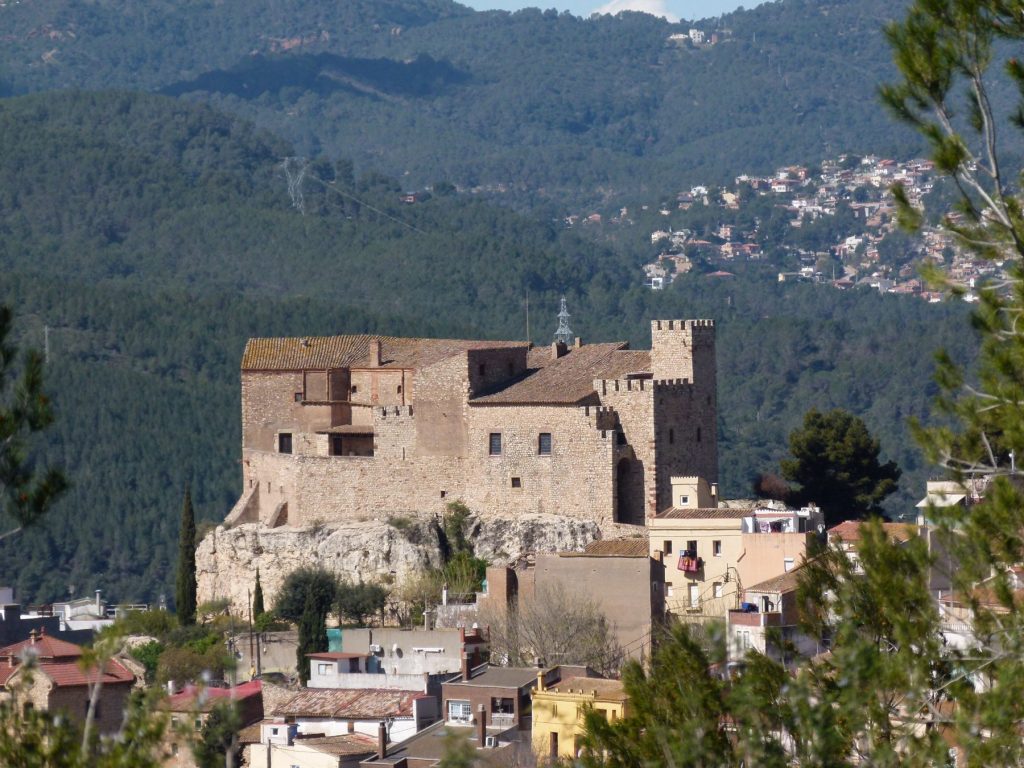 Castell del Papiol sobre su roca, dominando las casas del pueblo, con Collserola al fondo